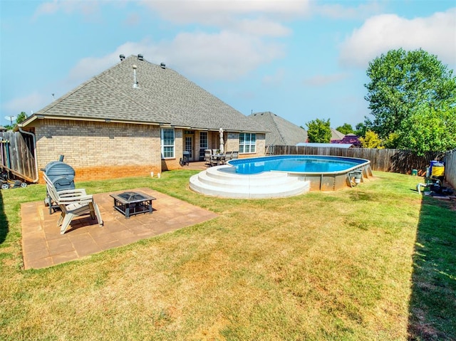 view of swimming pool featuring a fenced backyard, a fire pit, a lawn, a fenced in pool, and a patio area