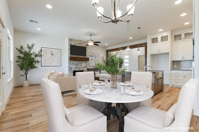 dining space with ceiling fan, a fireplace, and light hardwood / wood-style flooring