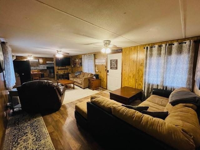 living room featuring ceiling fan, wooden walls, and hardwood / wood-style floors