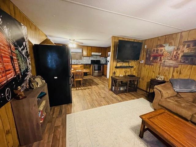 living room with light hardwood / wood-style floors and wood walls