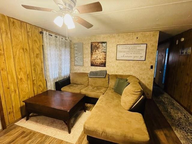 living room with wooden walls, ceiling fan, and light wood-type flooring