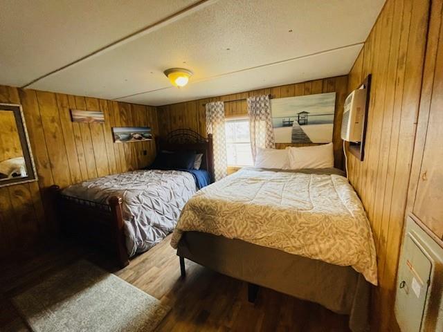 bedroom with light hardwood / wood-style flooring, wooden walls, and an AC wall unit