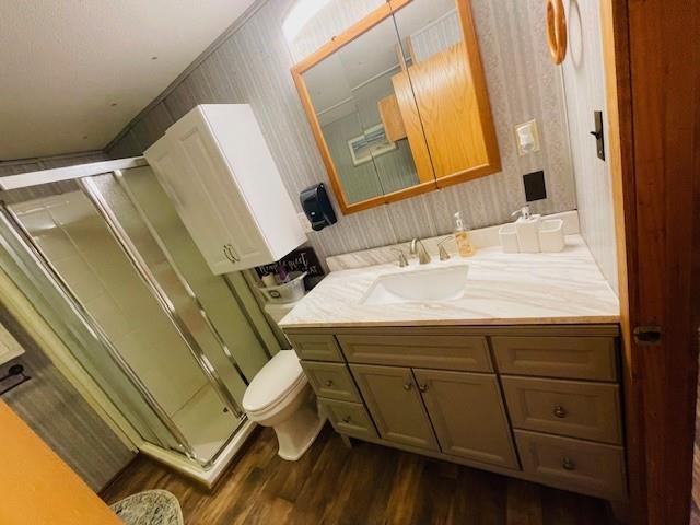 bathroom with hardwood / wood-style flooring, ornamental molding, a shower with shower door, and vanity