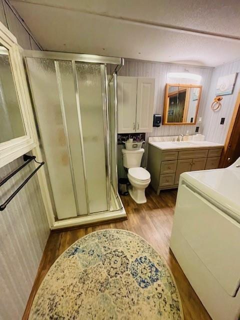 bathroom featuring washer / clothes dryer, vanity, toilet, and a shower with shower door