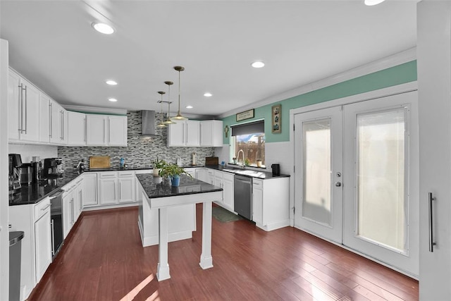 kitchen with a breakfast bar area, a center island, stainless steel dishwasher, pendant lighting, and wall chimney range hood