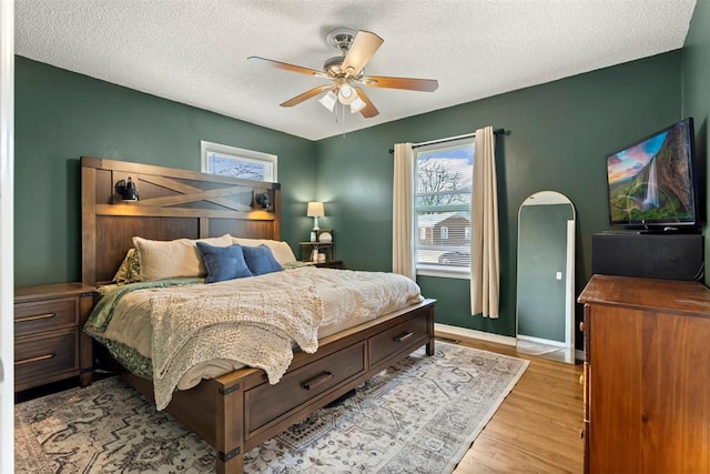 bedroom featuring light wood-style flooring, multiple windows, and a textured ceiling