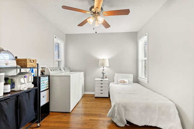 bedroom with ceiling fan, hardwood / wood-style flooring, washing machine and dryer, and a textured ceiling