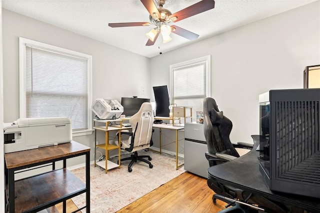 office space with light wood-type flooring, ceiling fan, a textured ceiling, and baseboards