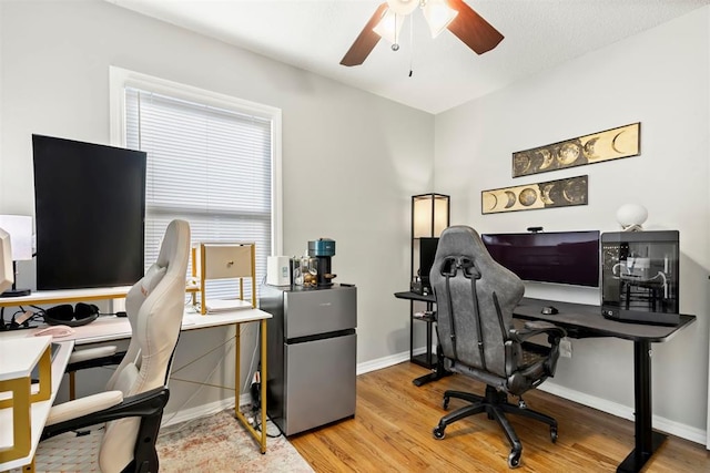 office featuring light wood-type flooring, a ceiling fan, and baseboards