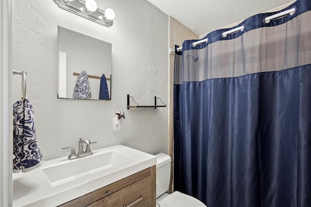 full bath with a shower with shower curtain, toilet, a textured wall, a textured ceiling, and vanity