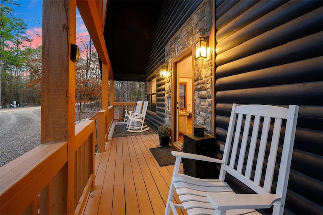 deck at dusk featuring covered porch