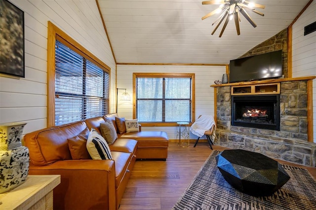 living room featuring vaulted ceiling, a stone fireplace, wooden walls, wood-type flooring, and ceiling fan