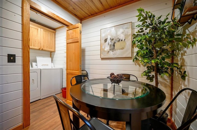 dining room featuring wood ceiling, washer and clothes dryer, light hardwood / wood-style floors, and wood walls