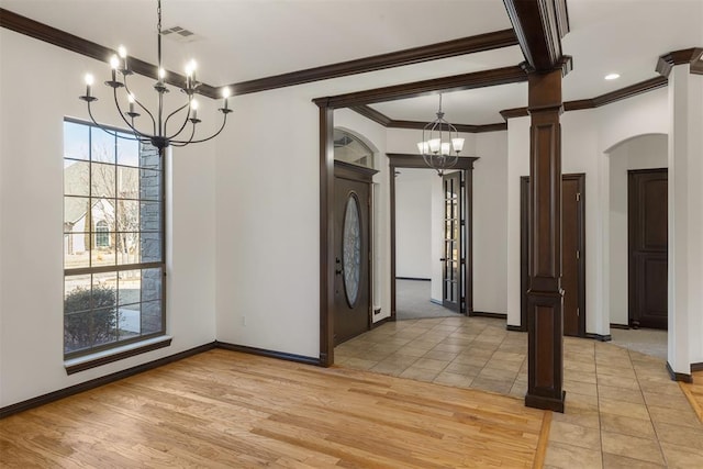 unfurnished dining area featuring an inviting chandelier, crown molding, light hardwood / wood-style flooring, and ornate columns