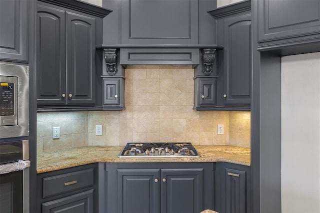 kitchen featuring stainless steel appliances, gray cabinetry, light stone counters, and decorative backsplash