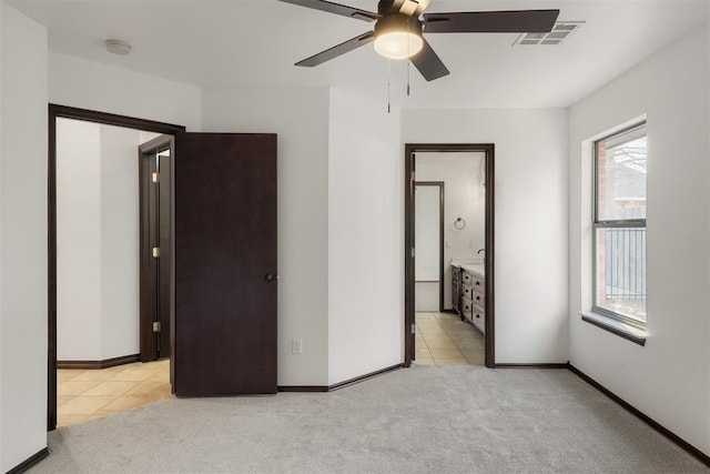 unfurnished bedroom featuring light colored carpet, ceiling fan, and ensuite bath