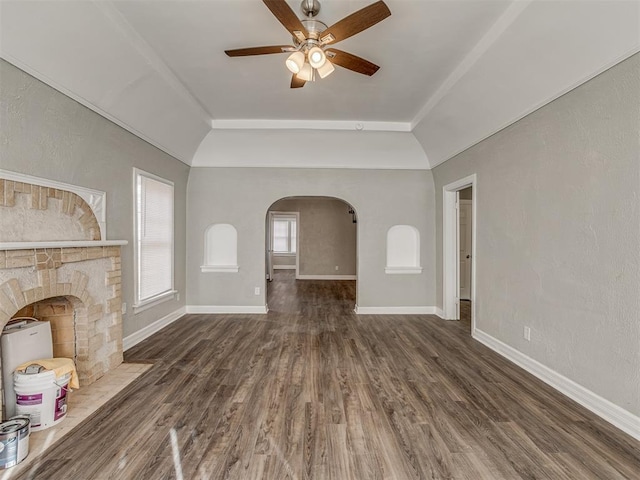 unfurnished living room featuring dark hardwood / wood-style flooring, a stone fireplace, vaulted ceiling, and ceiling fan