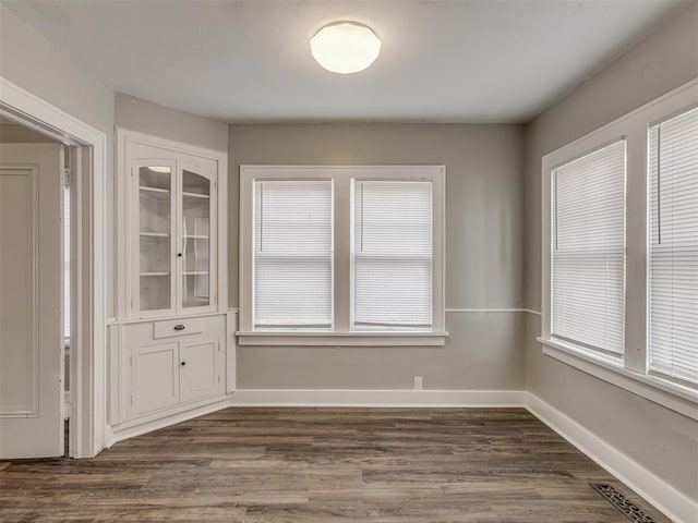 unfurnished dining area with dark wood-type flooring