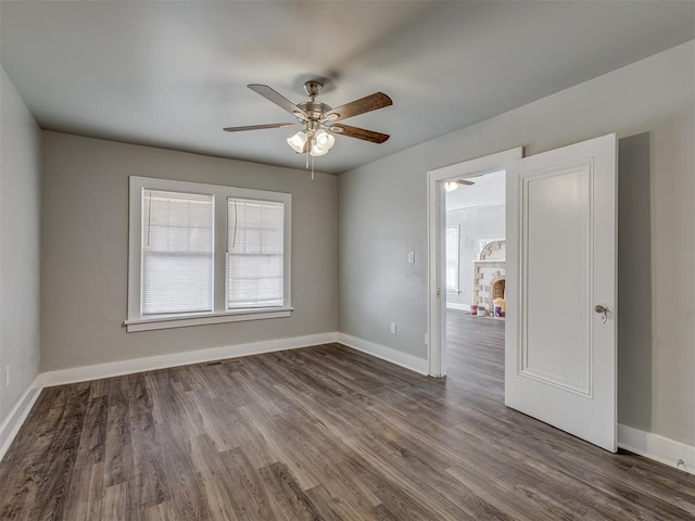 spare room with a stone fireplace, a wealth of natural light, and dark hardwood / wood-style flooring