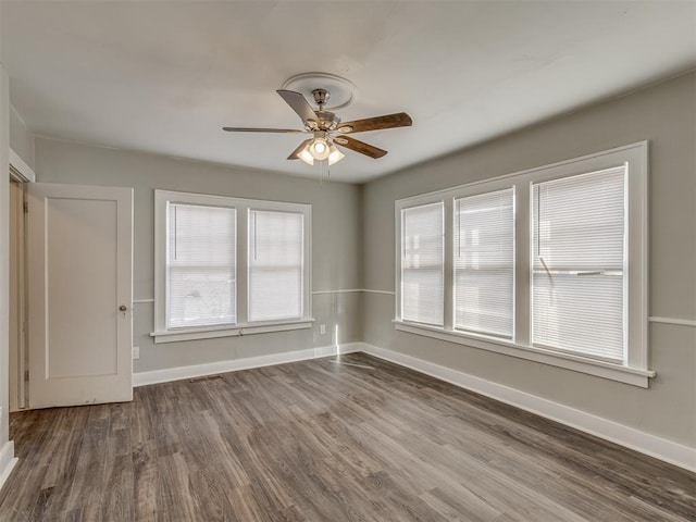 empty room with ceiling fan and dark hardwood / wood-style flooring