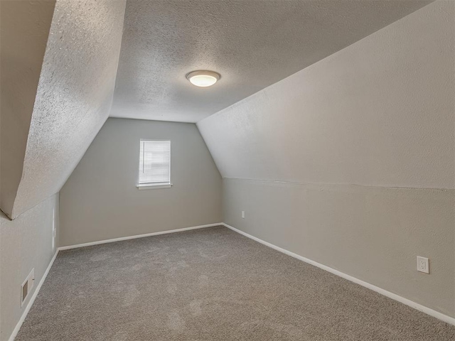 bonus room featuring vaulted ceiling, carpet, and a textured ceiling