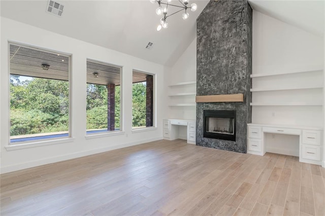 unfurnished living room featuring built in desk, high vaulted ceiling, a large fireplace, light hardwood / wood-style floors, and built in shelves