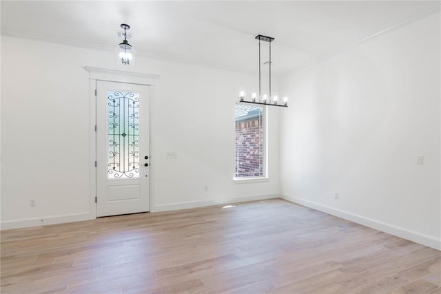 foyer entrance with ornamental molding, a chandelier, and light hardwood / wood-style floors