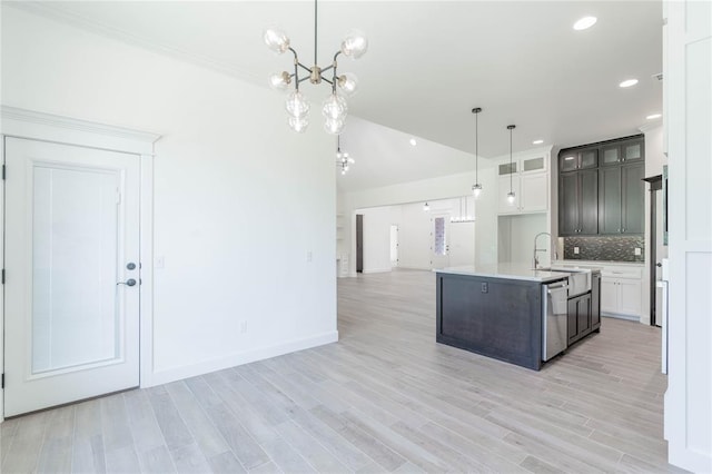 kitchen with pendant lighting, white cabinetry, a kitchen island with sink, decorative backsplash, and stainless steel dishwasher