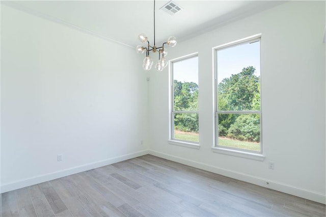 empty room featuring a notable chandelier, ornamental molding, and light wood-type flooring