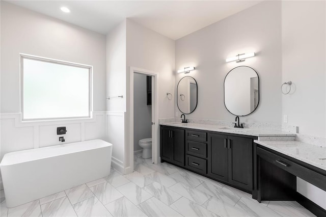 bathroom with vanity, toilet, and a tub