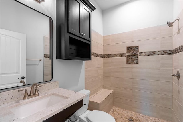 bathroom with a tile shower, sink, and toilet