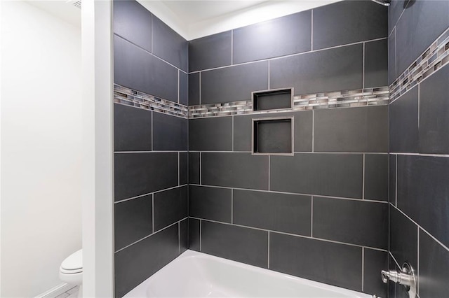 bathroom with tiled shower / bath combo and toilet