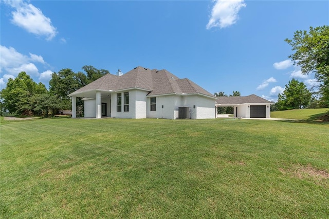 back of property with a garage, central AC unit, and a lawn