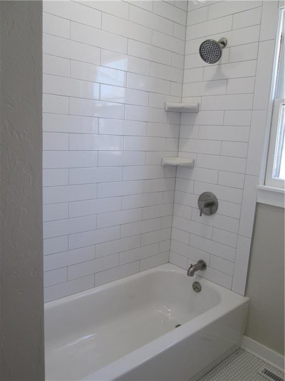 bathroom featuring tiled shower / bath combo and tile patterned flooring