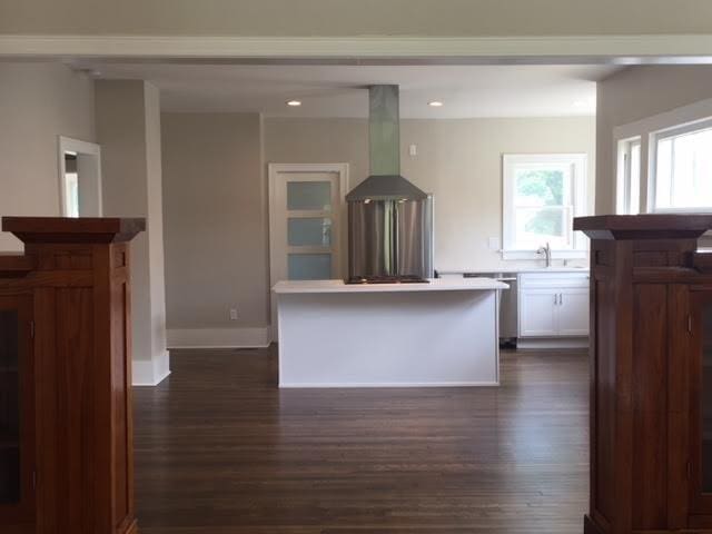 212 NE 15th St, Oklahoma City, OK 73104 - kitchen featuring ventilation hood, dark wood-type flooring, white cabinets, light countertops, and a kitchen island