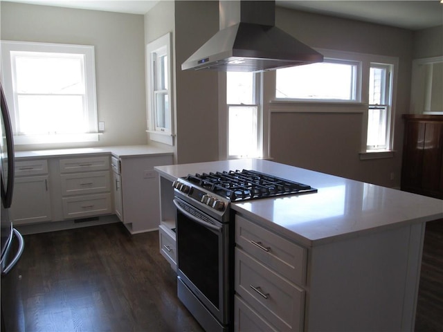 212 NE 15th St, Oklahoma City, OK 73104 - kitchen with wall chimney range hood, stainless steel range with gas stovetop, light countertops, dark wood finished floors, and a kitchen island