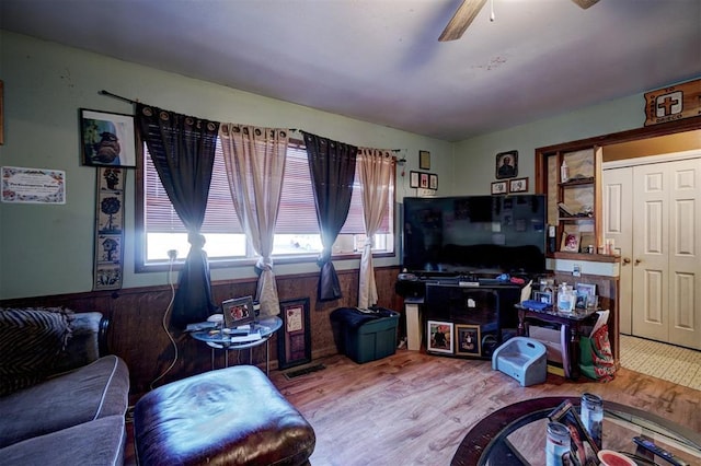 living room featuring hardwood / wood-style flooring, ceiling fan, and wood walls