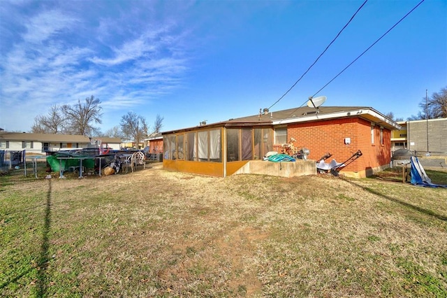 back of house featuring a sunroom and a lawn