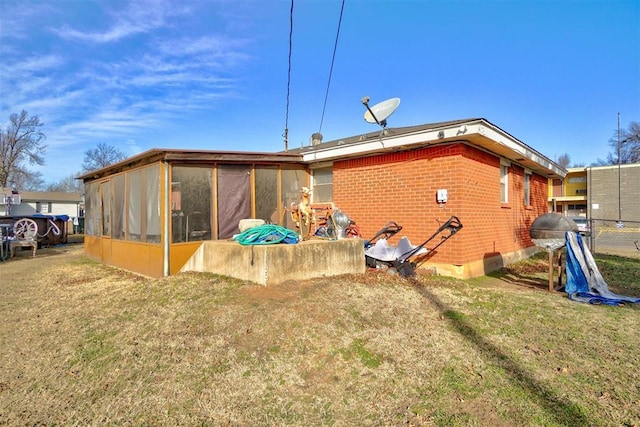 back of property with a lawn and a sunroom