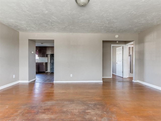 unfurnished room with a textured ceiling, baseboards, and wood finished floors