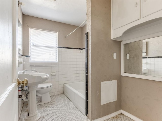 bathroom featuring bathing tub / shower combination, tile patterned flooring, toilet, and tile walls