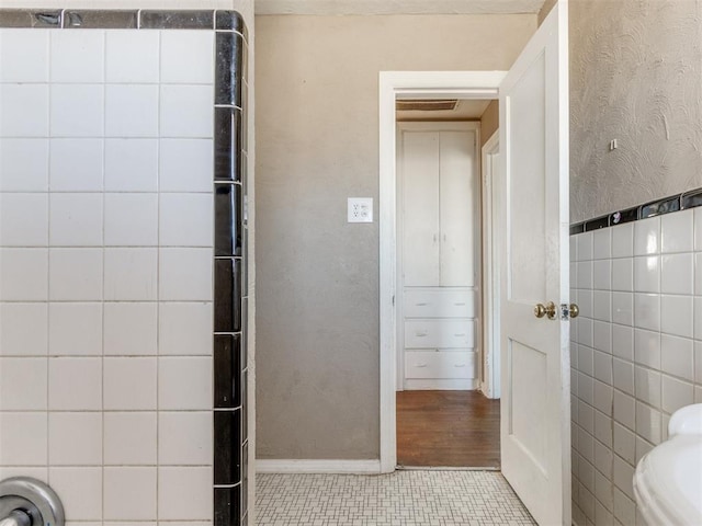 bathroom featuring toilet, tile walls, and tile patterned floors