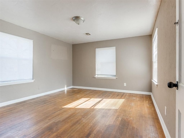 empty room with baseboards, visible vents, and light wood-style floors