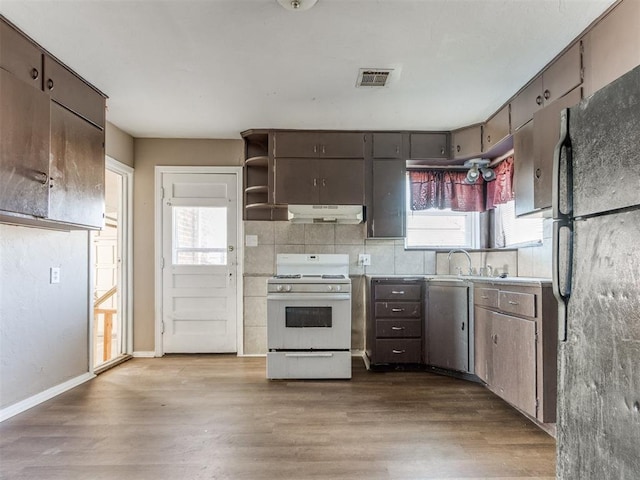 kitchen featuring white gas range oven, visible vents, wood finished floors, and freestanding refrigerator