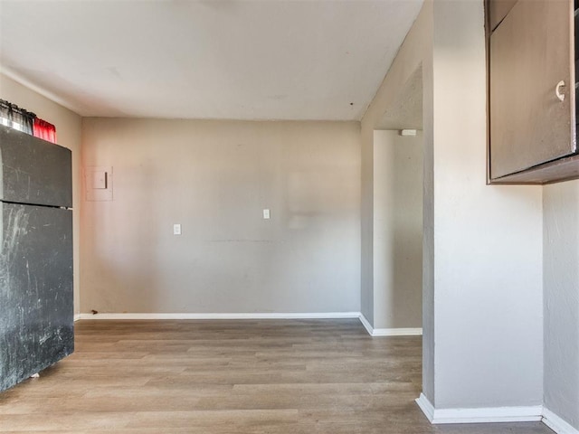 unfurnished room with light wood-style flooring and baseboards