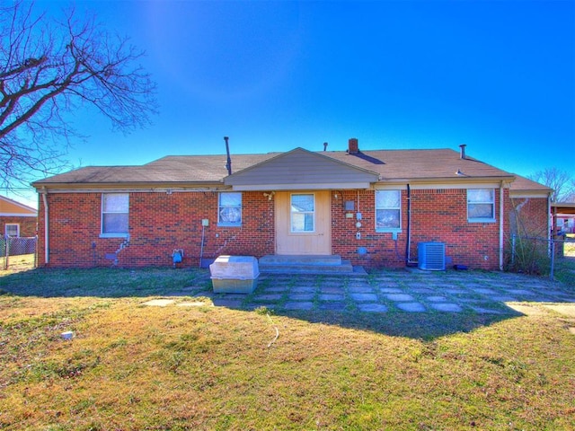 rear view of house featuring central air condition unit, brick siding, fence, and a yard