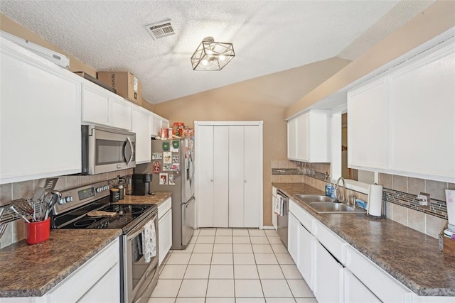 kitchen with lofted ceiling, sink, white cabinets, and appliances with stainless steel finishes