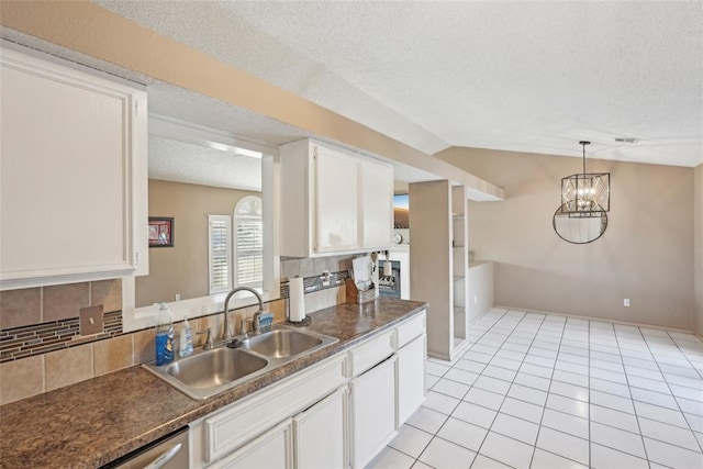 kitchen with sink, white cabinetry, vaulted ceiling, a textured ceiling, and backsplash