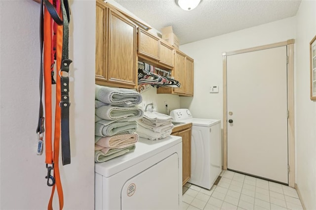 laundry area with cabinets, light tile patterned floors, a textured ceiling, and washer and clothes dryer