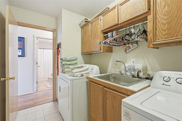 clothes washing area featuring cabinets, sink, washer and dryer, and light tile patterned floors